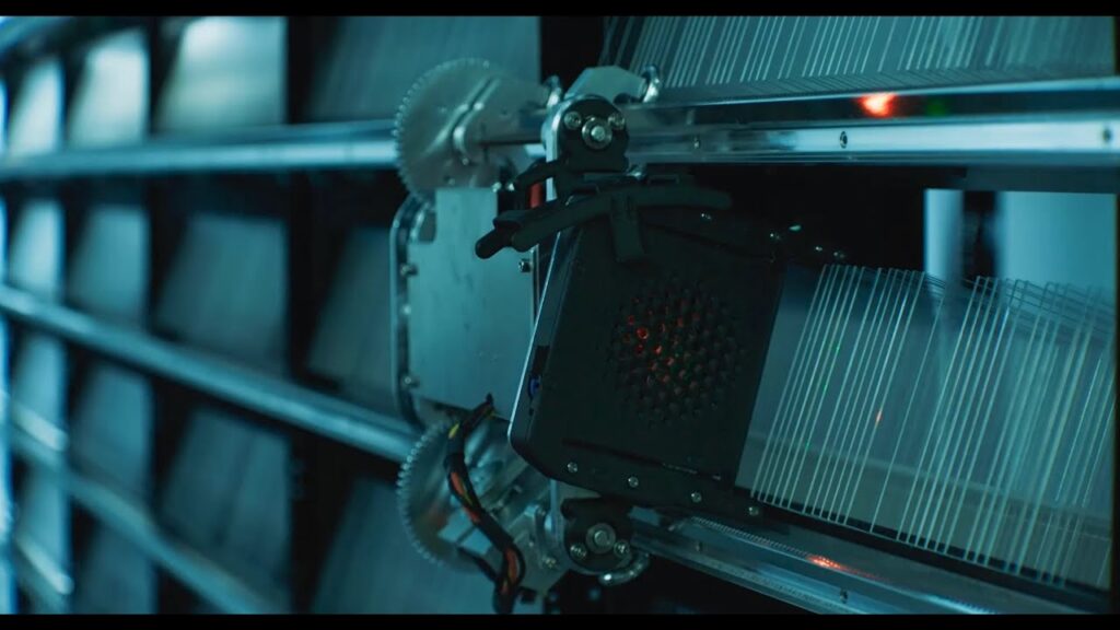 Zautomatyzowane ramię robota pobierające szklane nośniki danych z regału.