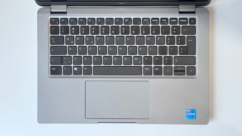 Wdok z góry na klawiaturę QWERTY i touchpad laptopa Dell Latitude 5320, widoczna naklejka Intel Core i5