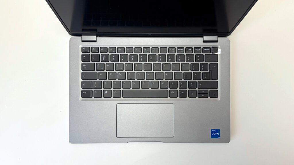 Widok z góry na klawiaturę QWERTY laptopa Dell Latitude 5420 oraz touchpad z naklejką Intel Core i5